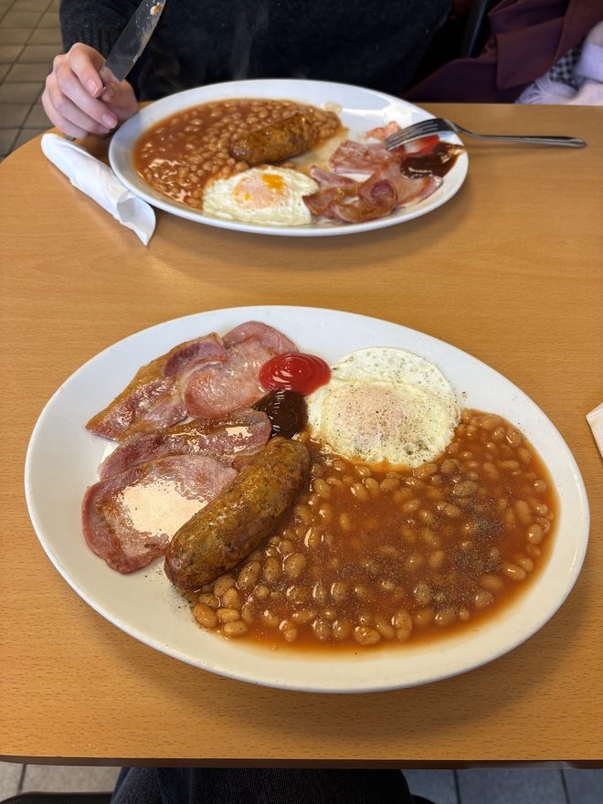 A full English breakfast plate with a second plate behind it.