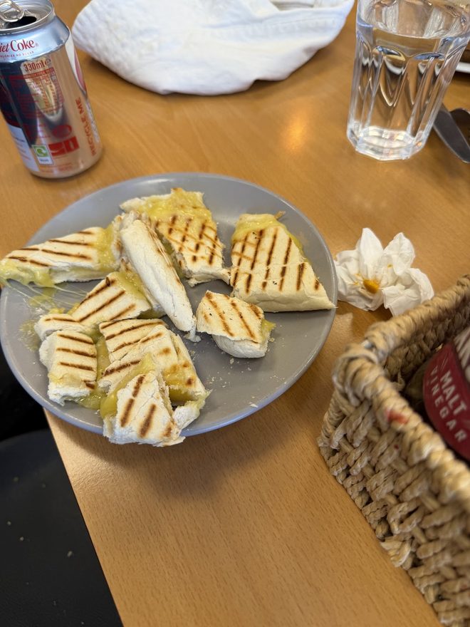 Grilled panini halves with a glass of water and a bread basket.