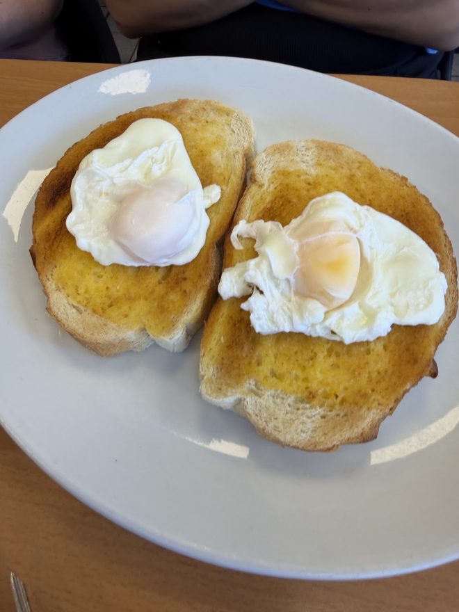 Two poached eggs on buttered toast on a white plate.