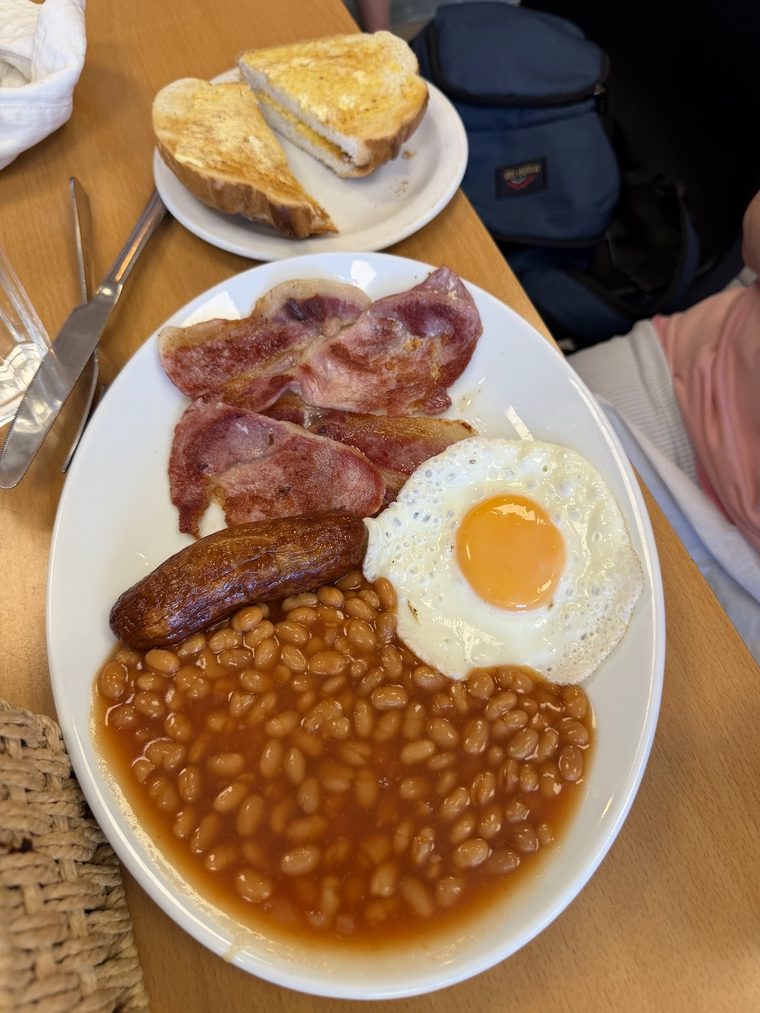 Bacon, sausage, fried egg and beans with a side plate of toasted sandwich.